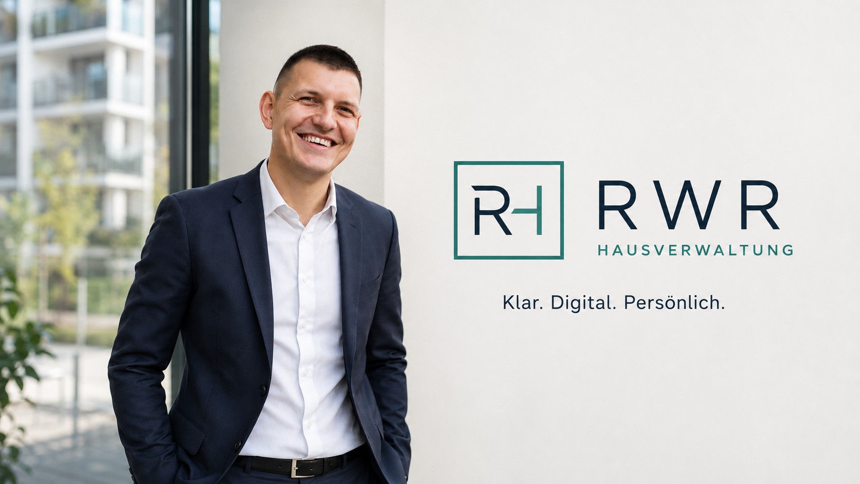 Lukasz Pawel Reiwer vor einem modernen Wohngebäude neben dem Logo von RWR Hausverwaltung